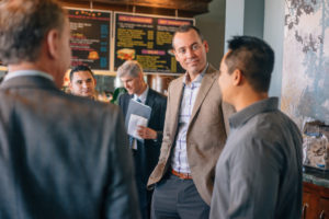 Image of people standing around a coffee shop discussing business