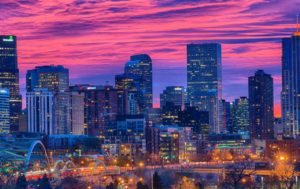 Image of sunset in Denver. The purple and pink clouds touch the top of the buildings downtown